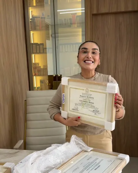Dra. Laís mostrando um diploma emoldurado no consultório